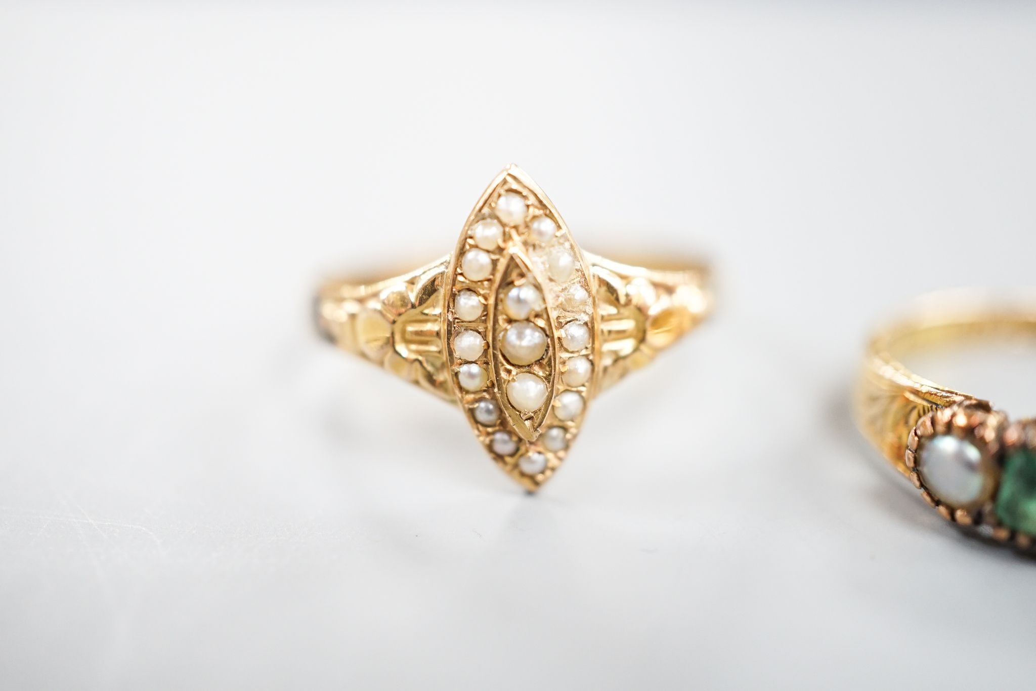 A Victorian 15ct gold, emerald and split pearl set five stone half hoop ring, size M, gross 1.9 grams and an early 20th century yellow metal and seed pearl set dress ring, size O, gross 1.7 grams.